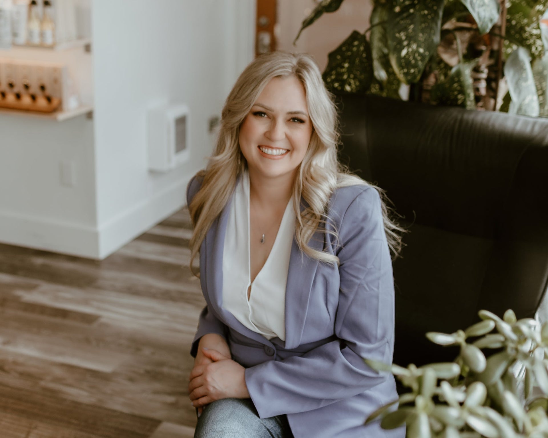 Woman sitting in a chair with plants and a shelf in the background