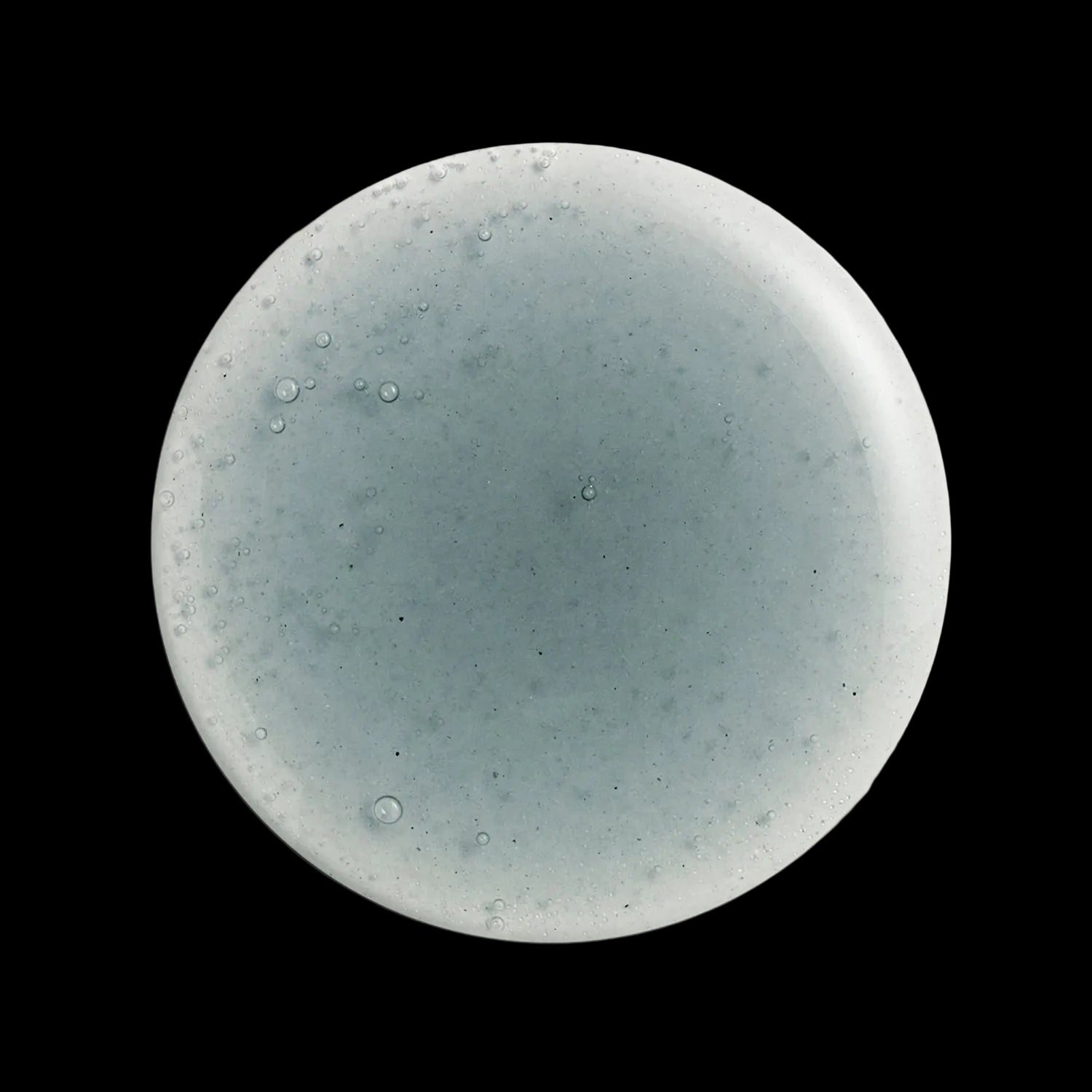 Round cleanser swatch with a speckled design on a white background