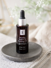 Rosehip Triple C+E Firming Oil bottle on a gray plate with a blurred natural background